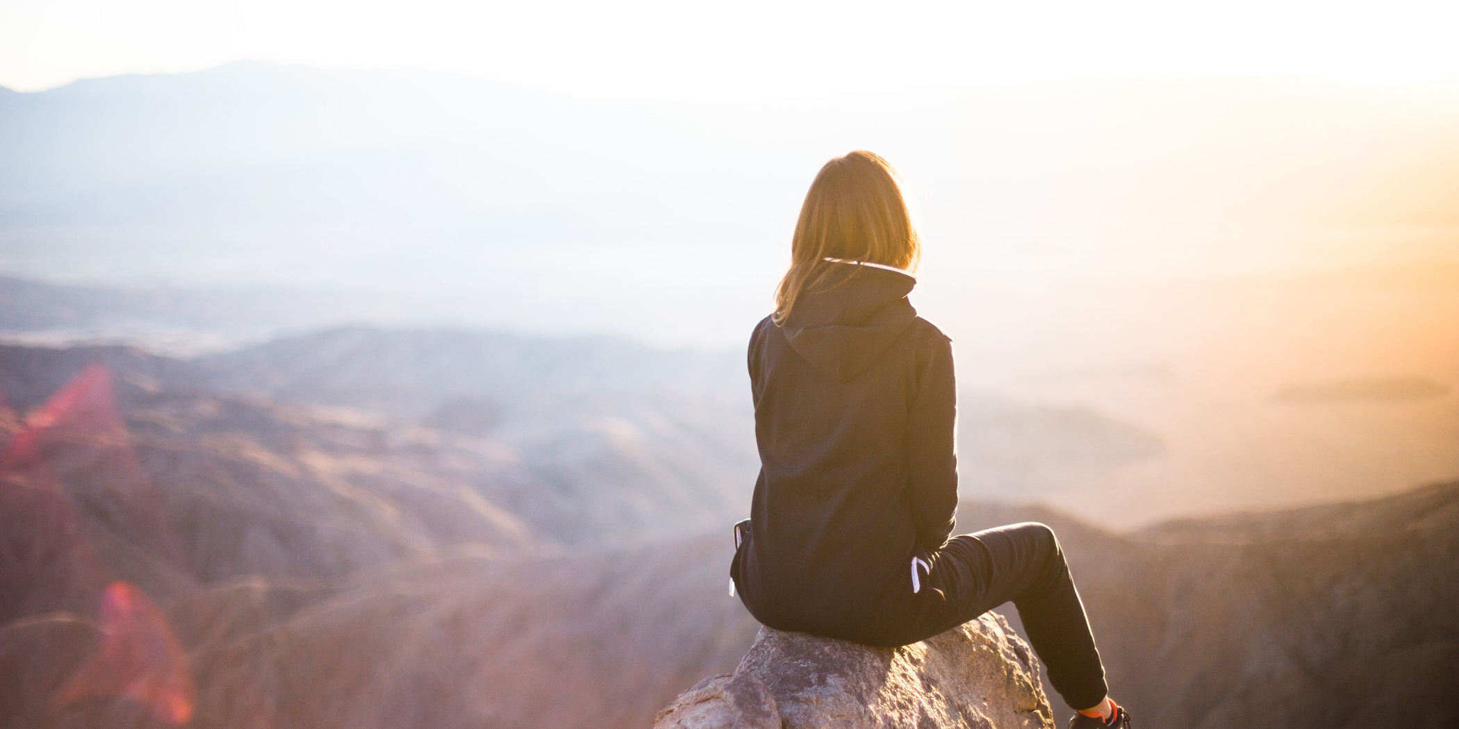 Image of woman looking out from the top of a mountain, for article about quality of life and the Bipolar Wellness Centre.