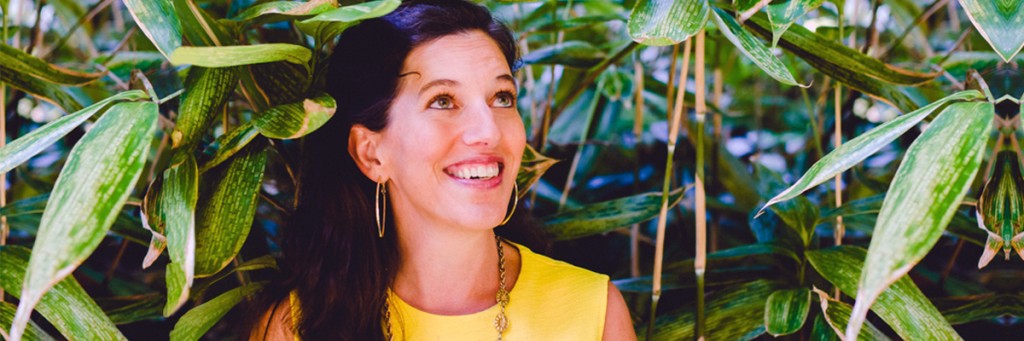 Victoria, a co-host to the online bipolar workshop, outside in front of a bush, smiling and looking up.