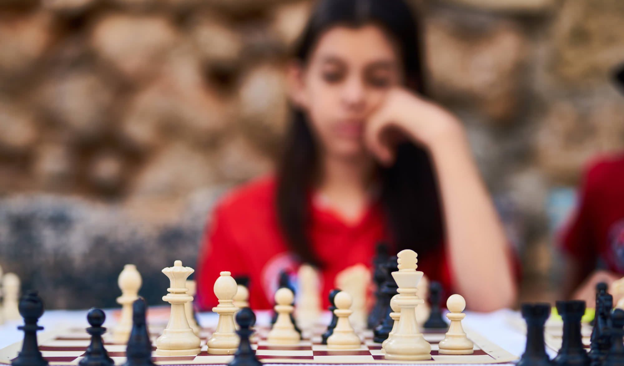 A woman pondering what move to make during a chess game, meant to represent cognition and possible bipolar brain damage.