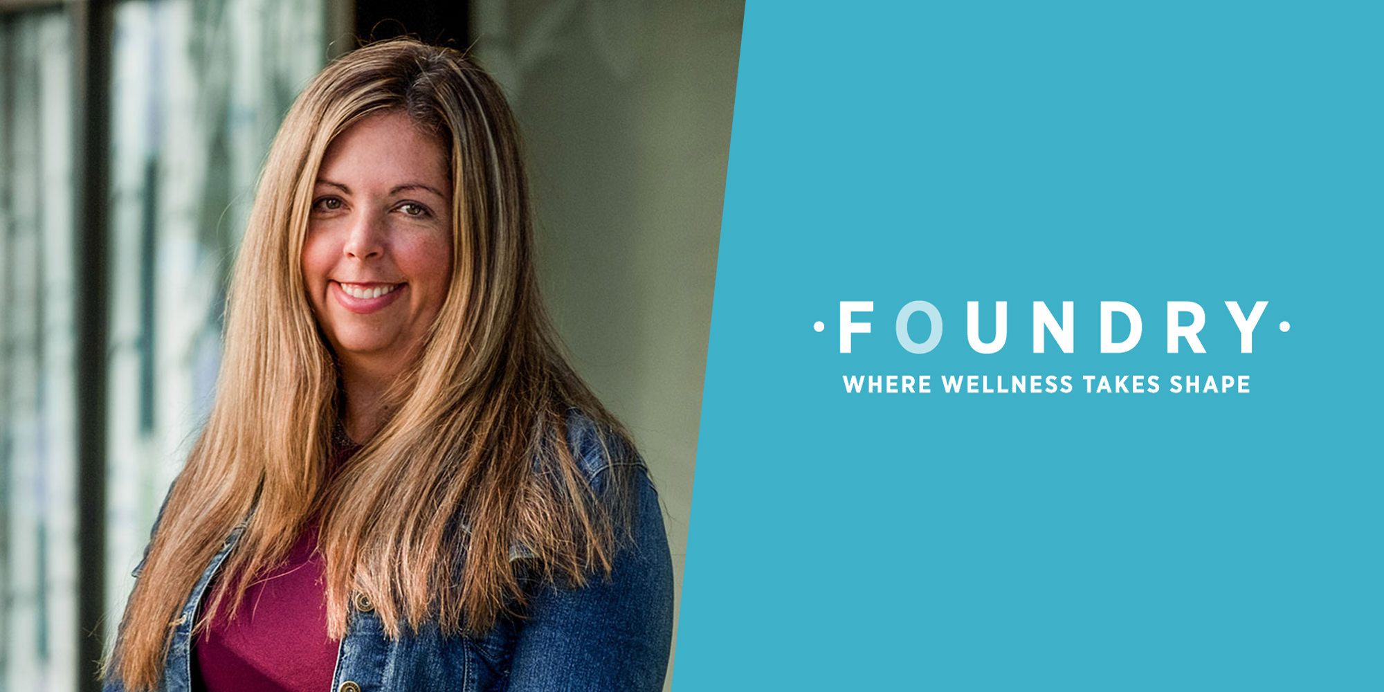 Dr. Skye Barbic is standing and smiling inside a university hallway. Light is filtering in through the window and there appears to be a forest outdoors. She has long dark blonde hair and is wearing a jean jacket and burgundy shirt. The image is cut in half with a diagonal blue shape, with the words 'Foundry: Where Wellness Takes Shape' printed in the middle.