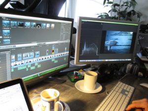 Two computer monitors with editor software on them, and two coffee cups on the desk.