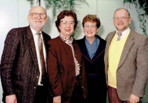 A younger Raymond in professional attire. He's standing next to four other people dressed professionally.