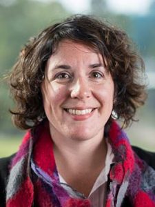 A headshot of Dr. O'Brien. She has short wavy brown hair and wearing a purple and red scarf. She is smiling.