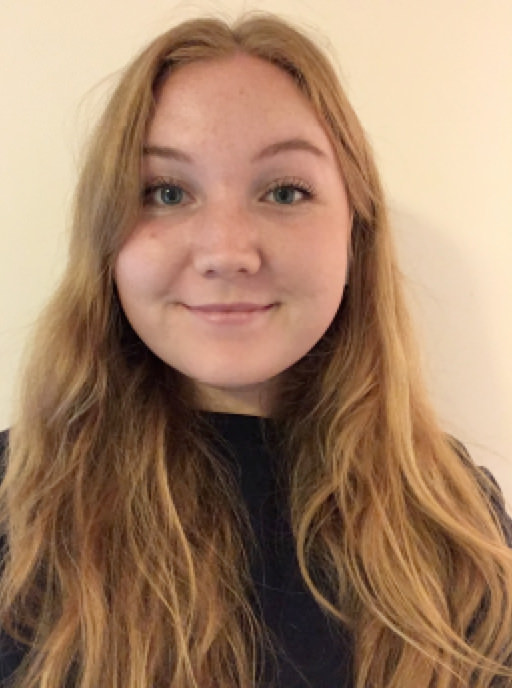 A headshot of Julia. She has long blonde hair and is wearing a black sweater. She is smiling.