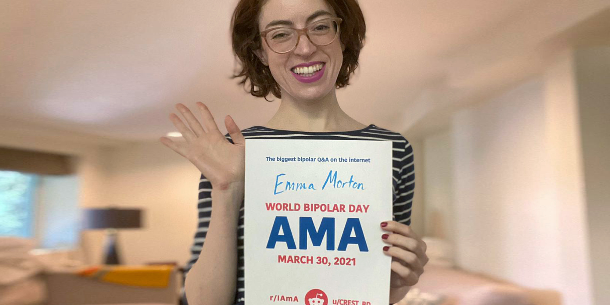 A headshot of Emma against a white background. She is Caucasian and has shoulder-length wavy red hair and rounded, tortoiseshell-patterned glasses.