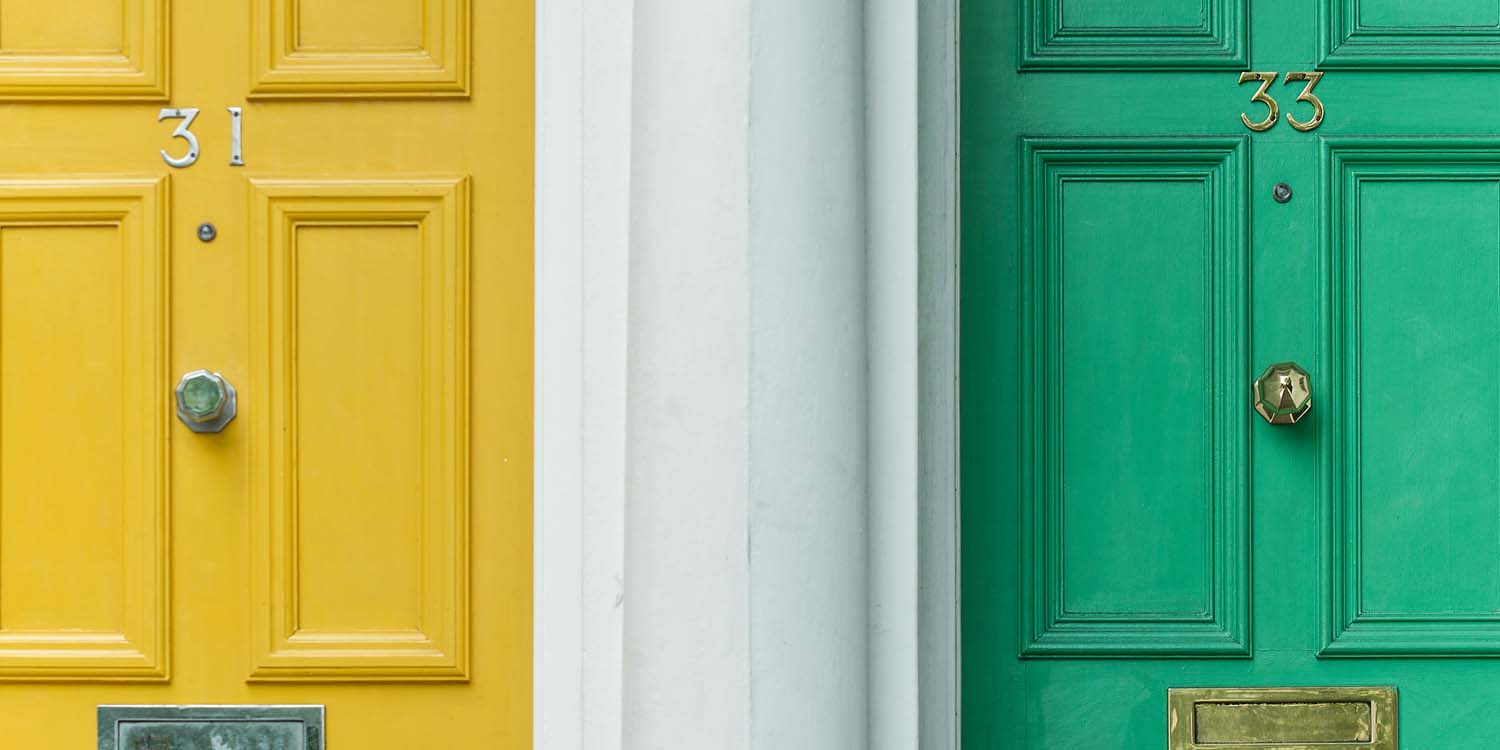 Two apartment doors side-by-side. One is bright yellow and labelled 31, and is on the left side. To the right is a vibrant green door labelled 33.